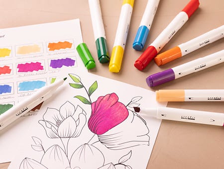 Papel con motivo parcialmente coloreado y rotuladores alrededor.