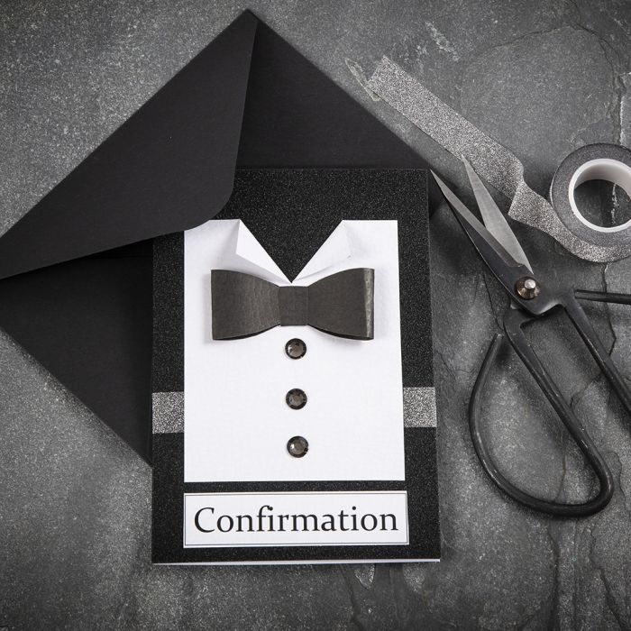 Una invitación en blanco y negro con una camisa y una pajarita hecha de papel texturizado y botones de piedras preciosas de imitación