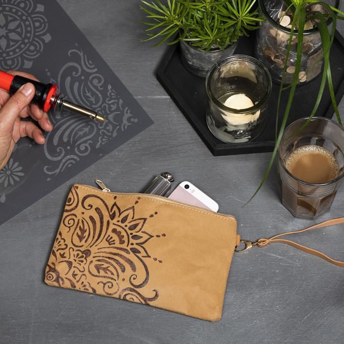 Una cartera de mano de papel imitación cuero con un diseño étnico usando una herramienta de pirograbado.