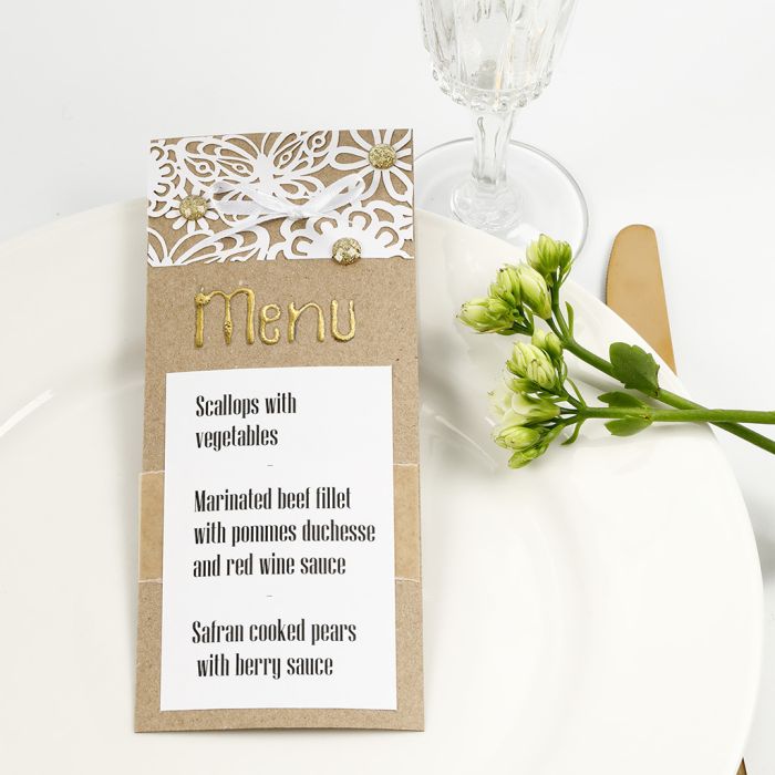Una carta de menú decorada con encaje de cartulina, papel de aluminio y joyas adhesivas.