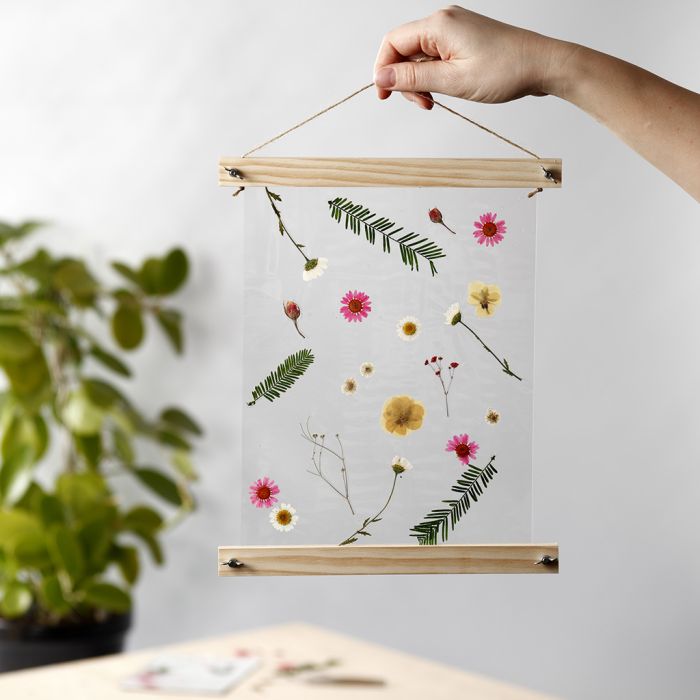 Una decoración colgante laminada con flores secas y colgadores para poster. .