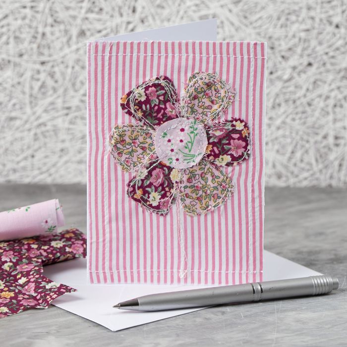 Una tarjeta de felicitación con un diseño de flor de tela cosida 