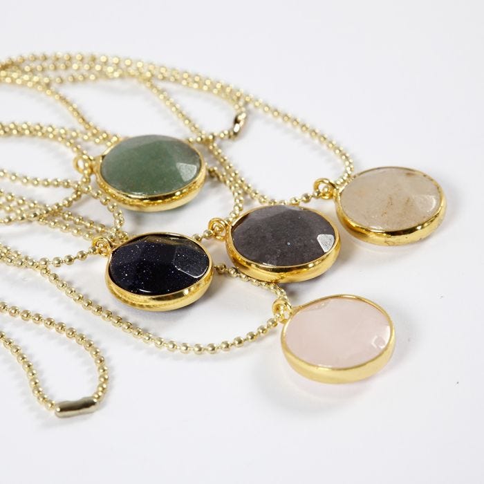 Un collar de cadena de abalorios y un colgante de joyería con una piedra