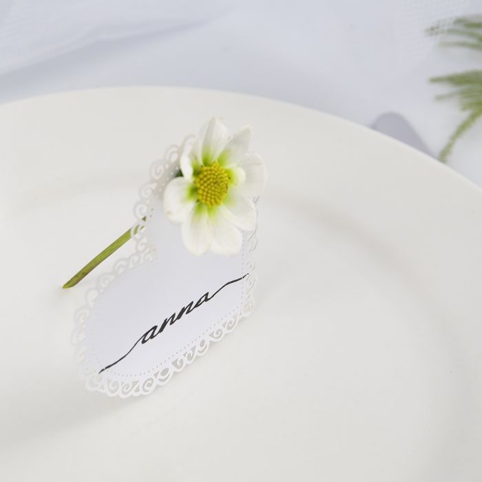 Una tarjeta de comensal de boda hecha de un corazón de tarjeta con una flor