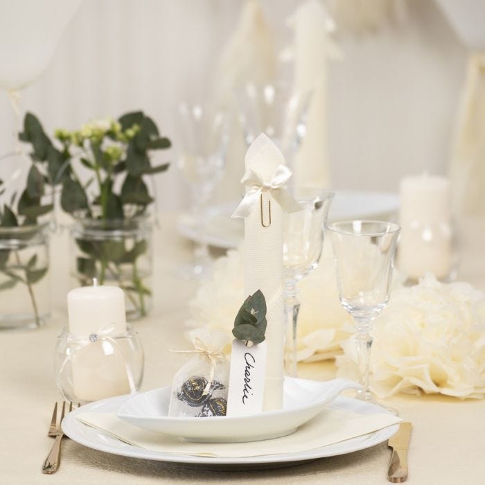 Decoración de mesa en blanco roto con flores de papel, , globos y tassels de papel de seda, una servilleta doblada como una torre