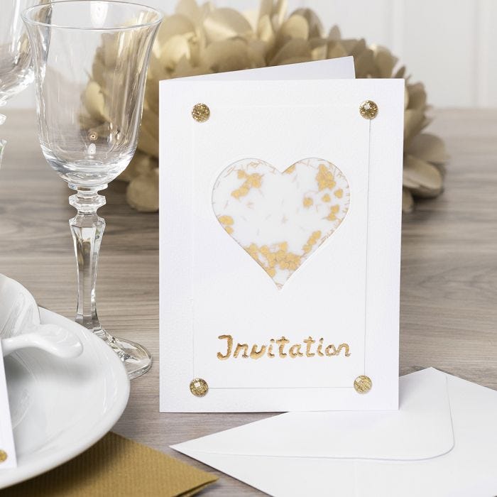 Una invitación decorada con un corazón de papel vellum, purpurina, pedrería y papel Deco Foil.