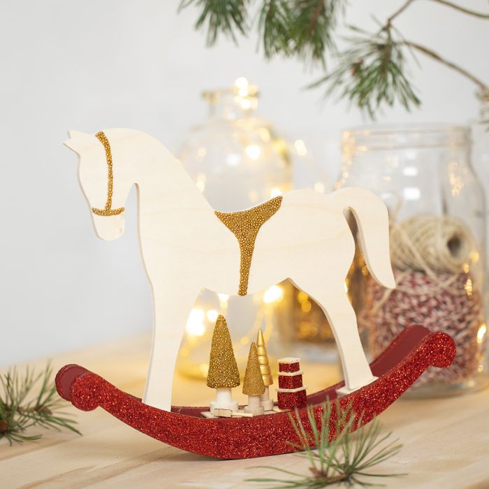 Un caballo de balancín con pequeños accesorios de madera decorado con pintura para manualidades, purpurina y cuentas.