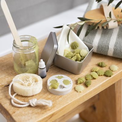 Recipiente de viaje con pequeños jabones de aceite de oliva y esponja de loofah