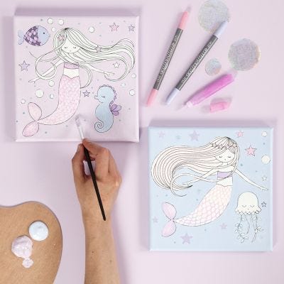 Un lienzo con un diseño de sirena decorado con rotuladores y pegamento glitter