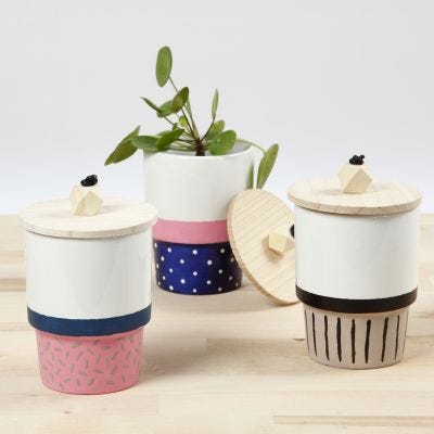 Una taza decorada con pintura de porcelana y una tapa con una cuenta de madera