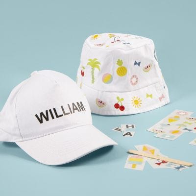 Un sombrero de cubo y una gorra decorada con pegatinas rub-on