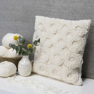 A cushion decorated with a punch needle design