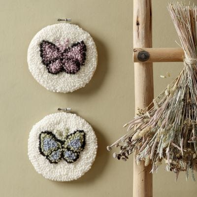 Mariposas bordadas con aguja perforadora en un bastidor para bordado.