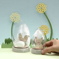 Una Campana Jar con figuras de Pascua de madera, huevos y plumas blancas